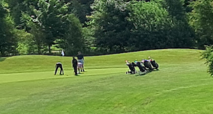 Øjebliksbillede fra sommerspillet, hvor et hold viser hvorledes man ifølge god golfetikette placerer sin vogn og bag ved greenen, så man hurtigt kan komme videre til næste hul,  og ikke sinker spillet.
